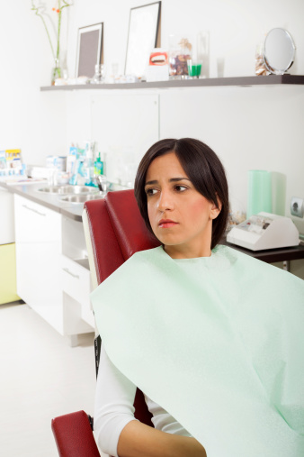 Anxious female patient in dental chair worried before having teeth extracted.