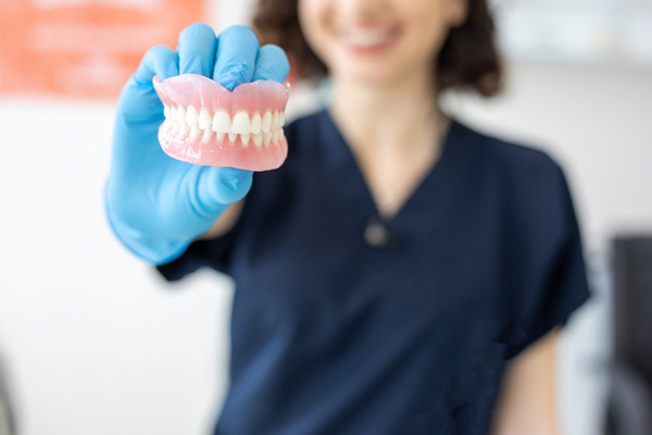 Person holding a set of dentures.