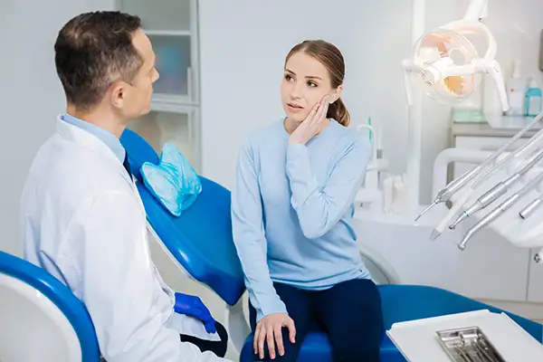 Concerned patient discussing tooth pain with the dentist while sitting in a dental chair.