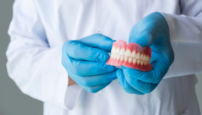 Dental professional holding modern dentures - dentures vs dental implants comparison at Higher Ground Dentistry Upland