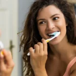 Woman brushing teeth during Dental Hygiene Month at Higher Ground Dentistry Upland