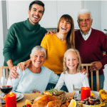 Family posing with bright smiles at a holiday dinner table, capturing the spirit of a Holiday Smile Makeover.