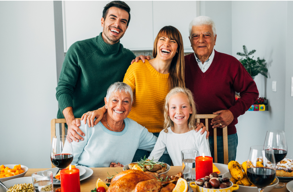 Family posing with bright smiles at a holiday dinner table, capturing the spirit of a Holiday Smile Makeover.