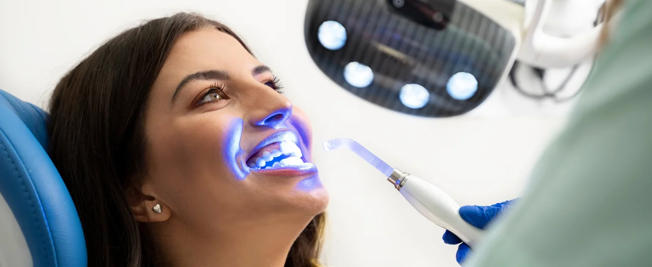 Smiling woman in dental chair at teeth whitening procedure