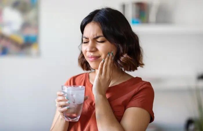 Woman with cold sensitivity needing urgent emergency dental care Upland appointment.