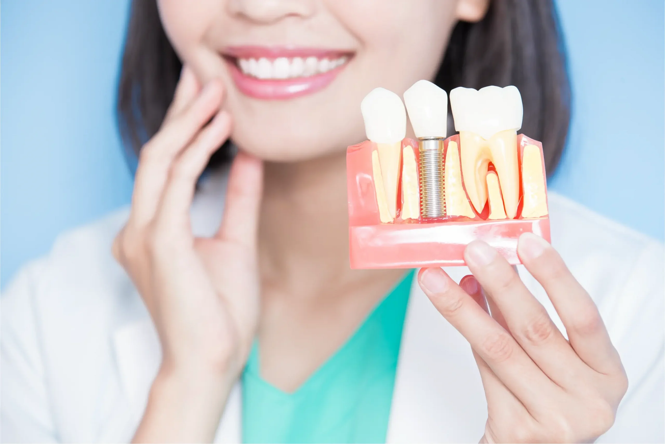 Dentist holding dental implant model smiling