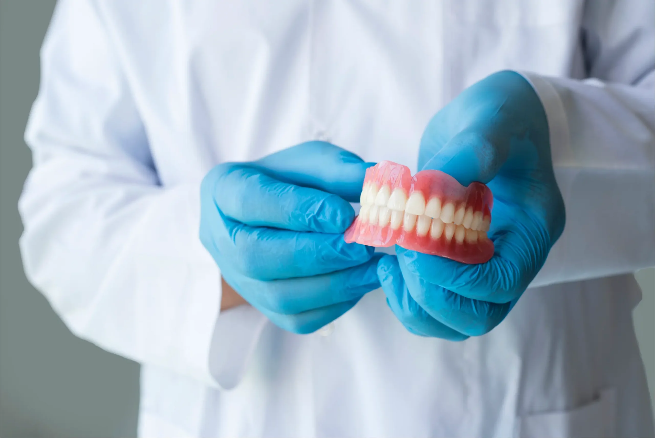 Dentist holding dental model in gloves.