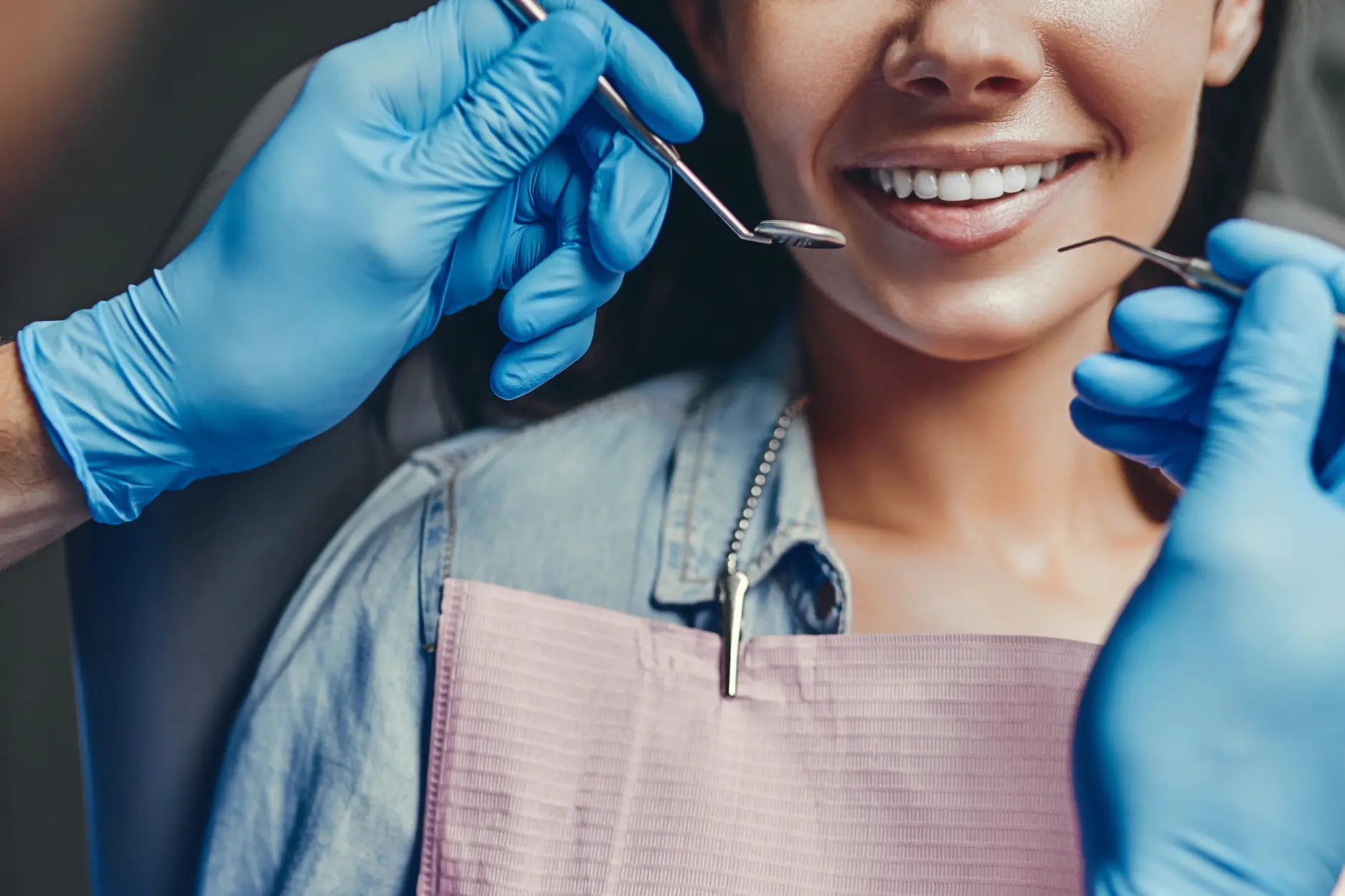 Pregnant woman smiling in dental chair with dentist wearing blue gloves examining her teeth