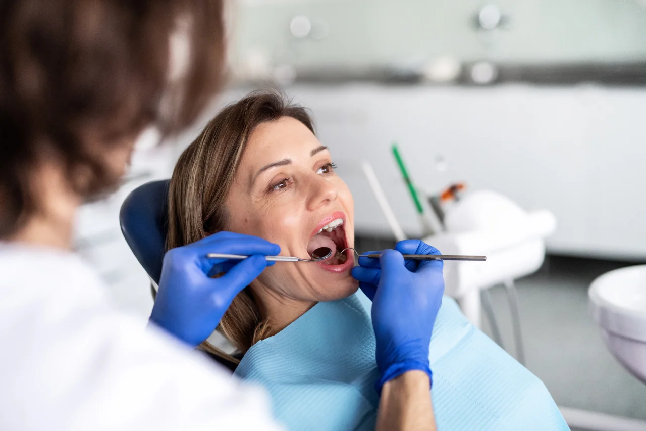 Patient in dental chair receiving routine dental examination from dentist