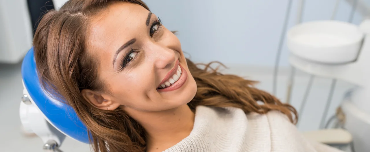 Smiling woman reclining in dental chair looking happy and confident