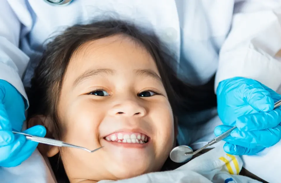 A friendly dentist at Higher Ground Dentistry in Upland showing a dental cleaning instrument to a child during a routine dental checkup for kids.