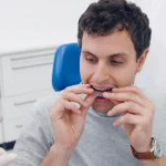 Adult patient holding Invisalign clear aligners at Higher Ground Dentistry in Upland CA with Dr. Sikka