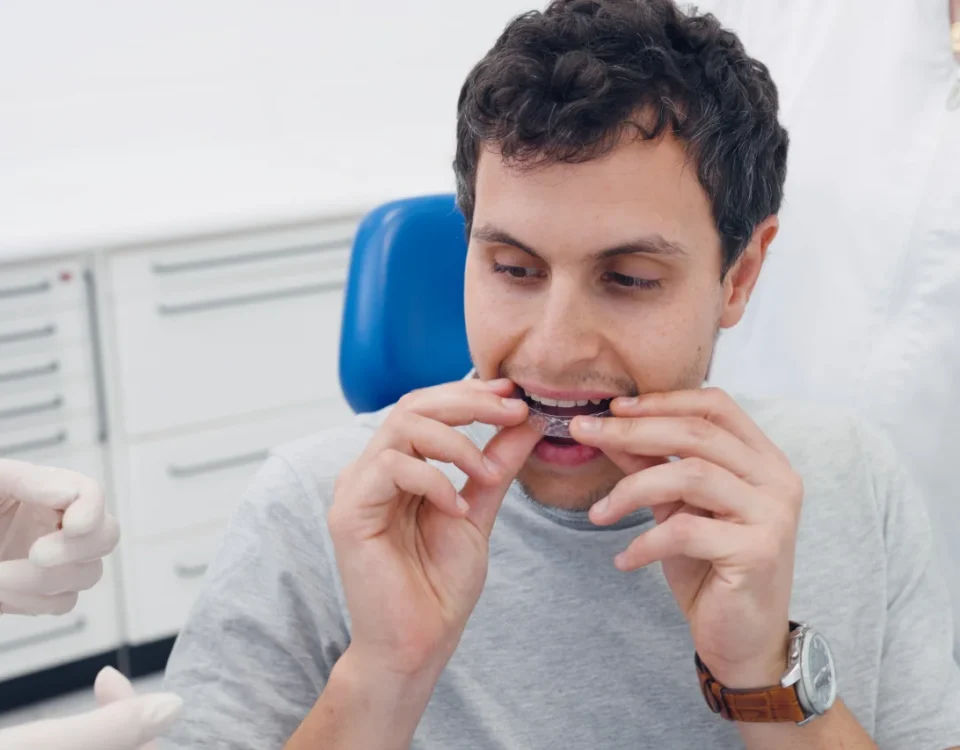 Adult patient holding Invisalign clear aligners at Higher Ground Dentistry in Upland CA with Dr. Sikka