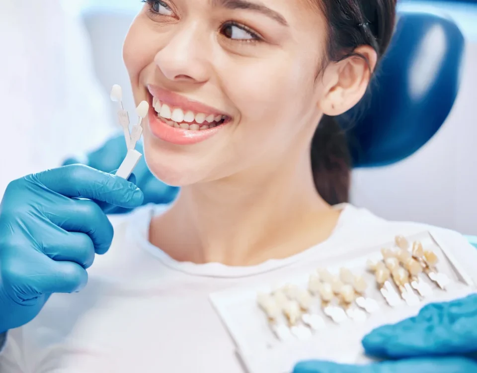 Dentist showing porcelain veneer shade options to a smiling patient during a veneers consultation at Higher Ground Dentistry in Upland CA