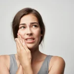 Woman holding jaw in pain from dental emergency upland showing cracked tooth pain upland symptoms at Higher Ground Dentistry