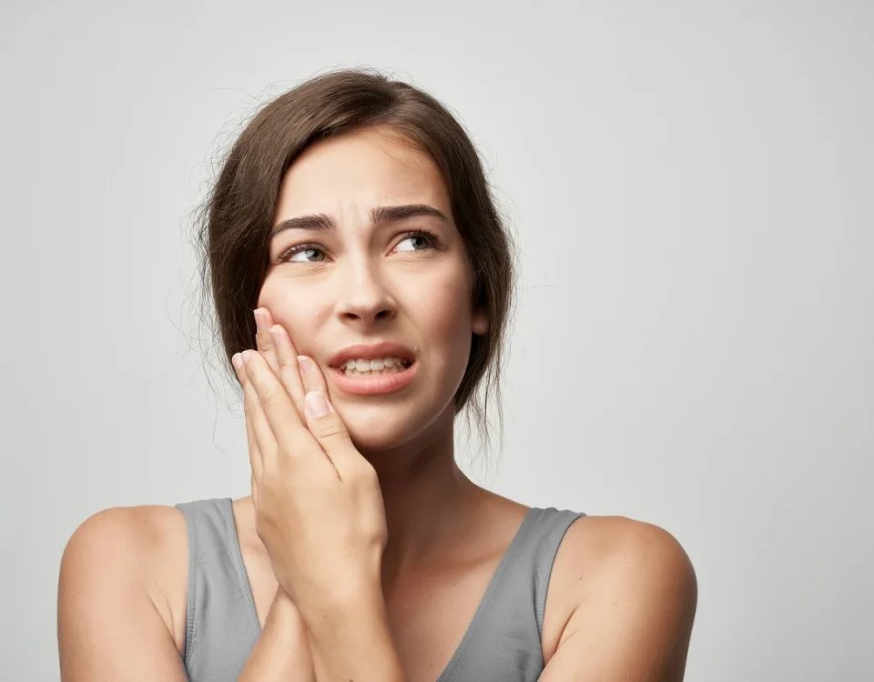 Woman holding jaw in pain from dental emergency upland showing cracked tooth pain upland symptoms at Higher Ground Dentistry