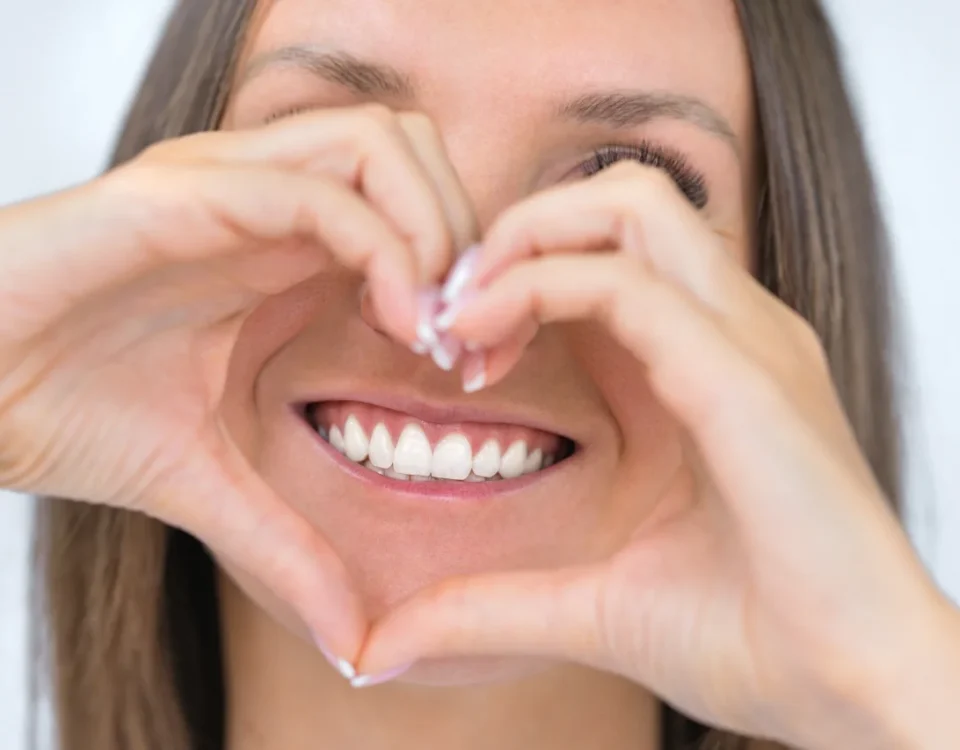 Woman making heart shape with hands showing healthy smile during National Smile Month at Higher Ground Dentistry dentist upland ca