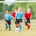 Kids playing soccer during summer sports season representing the need for dental protection and custom mouth guards to prevent cracked tooth upland injuries