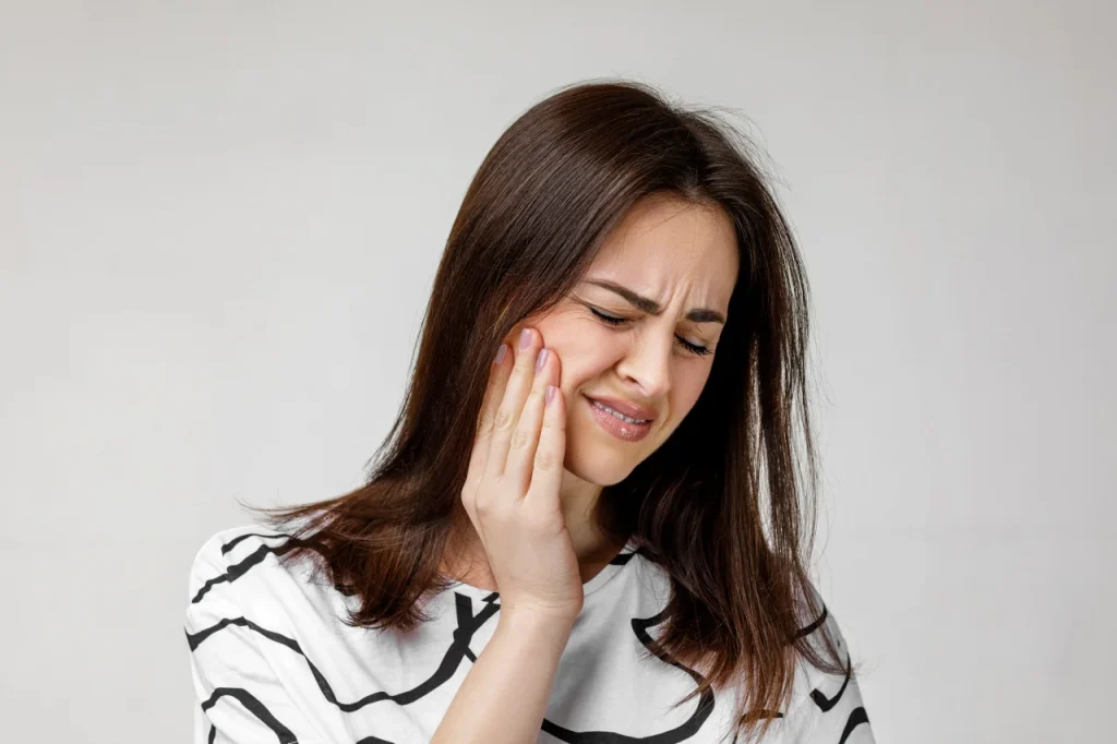 Woman experiencing pain from a swollen gum around one tooth