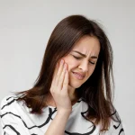 Woman experiencing pain from a swollen gum around one tooth